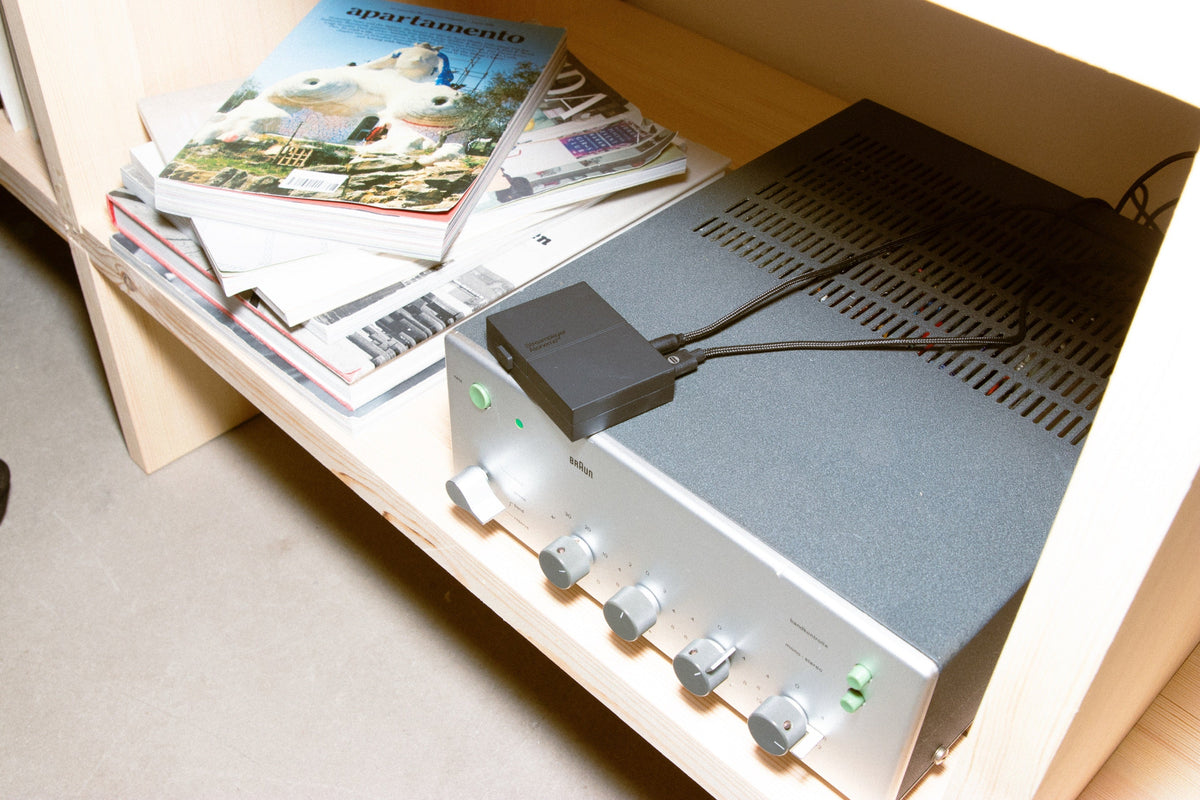Streamplayer on top of a silver Braun amplifier on a wooden shelf
